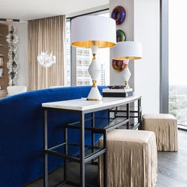 Portfolio: High-rise living room with fringed stools, cobalt sofa and geometric table lamps