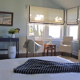 Master bedroom with bold navy pattern, roman shades, navy console table