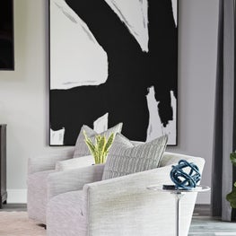 Large scale black and white abstract art with soft gray seating and neutral rug.