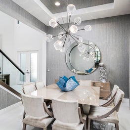 SLEEK CONTEMPORARY METALLIC RESIDENCE metalic walls, sunburst chandelier, large round mirror, taupe dining chairs, teal art glass