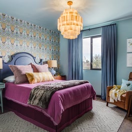 Family-friendly bedroom with purple bedding, leather recliner, and striped lamps