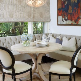 Upholstered banquette with round washed wood dining table, bowl shell pendant