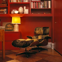 Chinese red wall & Herman Miller bookcases & an Eames chair upholstered in hide