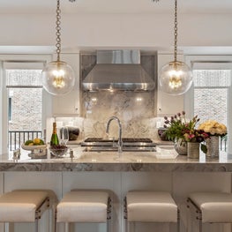 Symmetrical Sphere Pendant Lights, marble island and backsplash, leather stools.