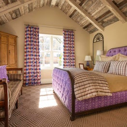 A fun, colorful but practical cottage bedroom with exposed wood beams