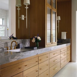 Custom millwork with reeded glass towers and brass finger pulls elevates the vanity wall with tailored detail.