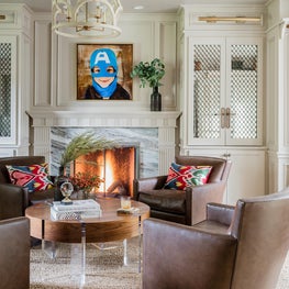 Cozy transitional living room library with fireplace and leather swivel chairs