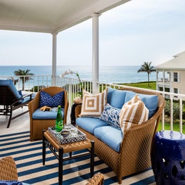 Natural, woven outdoor seating with comfortable light blue pillows & ocean views