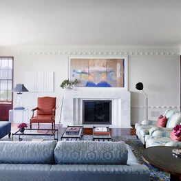 Vibrant modern art becomes a focal point on a white wall above a marble mantel 