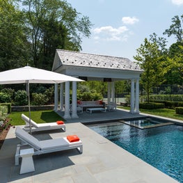 Modern pool house, bluestone patio, white metal recliners, large parasol