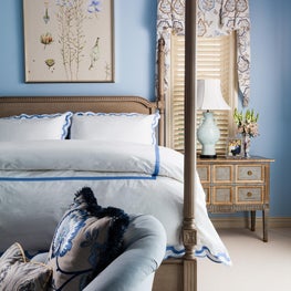 The bedroom has a palette of whites and blues that ground the antique furniture 