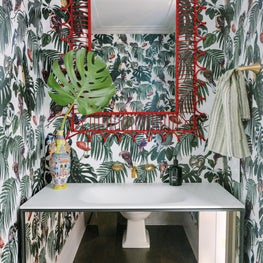 Whimsical Powder Bath with patterned wallpaper, red mirror, and floating vanity