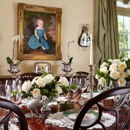 A glossy hardwood dining table is accented by fresh flowers.