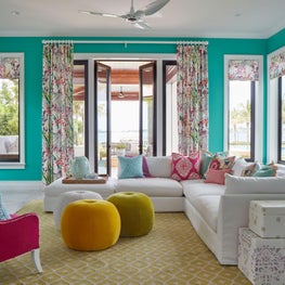 Deep turquoise walls and a kaleidoscope of colorful poufs in this modern family room