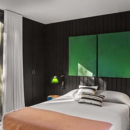 Modern bedroom with black paneled walls, green accents, floor to ceiling window