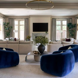 Portfolio: A custom living room layers tailored seating, cobalt velvet lounge chairs, sculptural cocktail tables, and contemporary artwork.