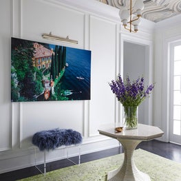 Gallery with custom print ceiling, wainscoting, and tulip pedestal table