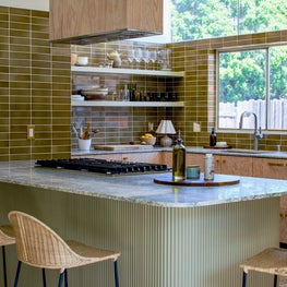 Eclectic Kitchen Design with Elongated Modern Gloss Ceramic Tile, Statement French Marble and a Lacquered Reeded Island and Wicker Counter Stools