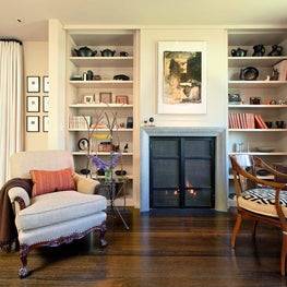 Living room with shelving built-in, fireplace, warm palette