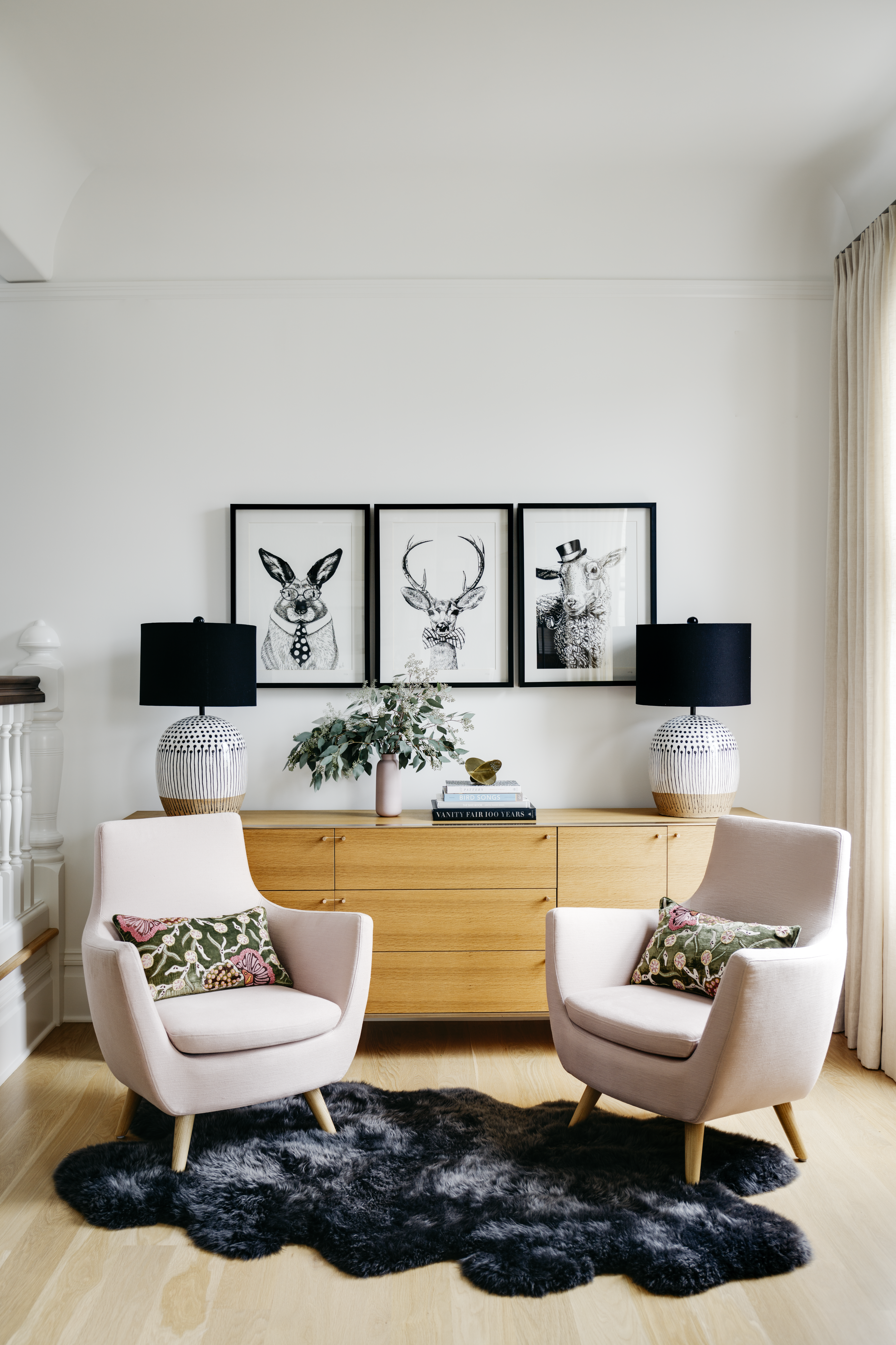 Eclectic sitting area with pink Scandinavian chairs and black and white artwork
