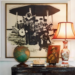 Jazzy entrance hall with a black and white second line brass band painting over another of a guitar player.