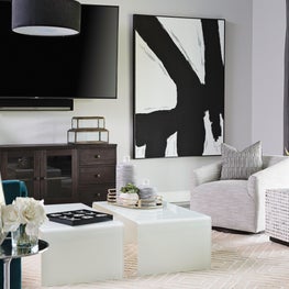 Neutral walls and rug with edgy artwork, modern waterfall tables and teal sofa.