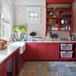 Three Barn Farm Laundry Room. Red cabinetry with farmhouse skink & rooster print wallpaper.