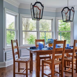 Kenilworth Kitchen. Breakfast/dining area with blue walls, dark chandeliers & medium wood dining set with wicker seats.