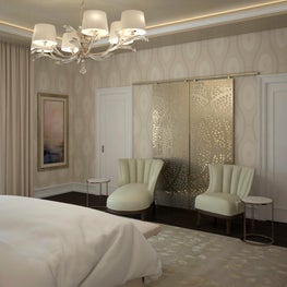 The decorative metallic wall hanging is framed by two midcentury accent chairs.