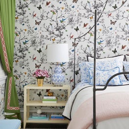 Bright bedroom with butterfly wallpaper, green curtains, black iron bed