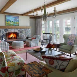 Three Barn Farm Family Room. Wooden beam ceiling with stone fireplace & French Country chandelier.