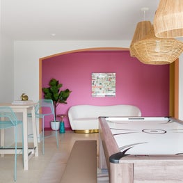 Portfolio: A game room in Pebble Beach, CA with a bright pink wall, aqua mesh bar stools, bungalow pendants, and an air hockey table.