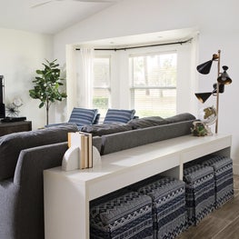 Blue & white upholstered ottomans tucked into sleek white console table.