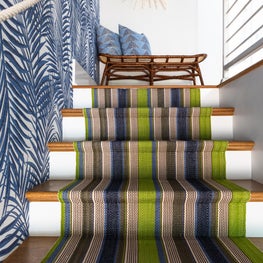 Palm Leaf wallpapered entry way with a rope hand rail & striped runner staircase