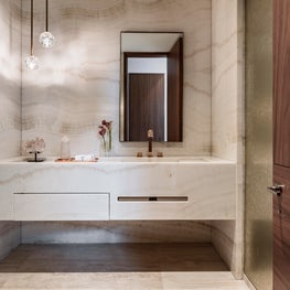 Vanity featuring book matched white onyx and silver leaf wallpaper