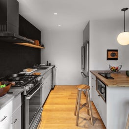 Kitchen with orb pendant, cool grey walls, open shelving, wood block island