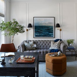 Classical living room with Chesterfield sofa, black sconces, wainscoting