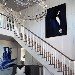 Large Hamptons foyer with open chandelier and wainscotting
