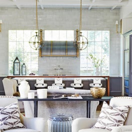 Kitchen with high ceilings, oversize hood, and long wooden breakfast bar