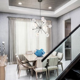 SLEEK CONTEMPORARY METALLIC RESIDENCE metalic walls, sunburst chandelier, large round mirror, taupe dining chairs, glass stairwell
