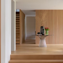 Entry hall with wood paneled wall, stair case, and living room bar