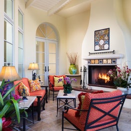 White backdrop with colorful patterned furniture surrounding tiled fireplace.