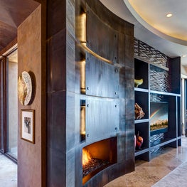 The curved wall that surrounds the actual fireplace is artistic and functional