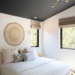 Platform bed, contemporary lighting, and dark blue-grey painted ceiling in bright master bedroom