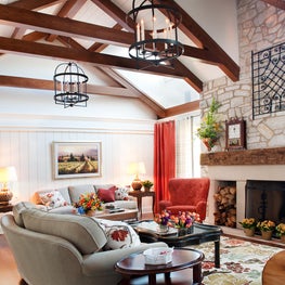American Lodge Family Room. Planked, beamed and trussed vaulted ceiling with lanterns, stone fireplace & coral accents.