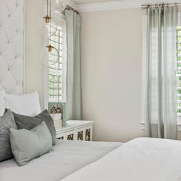 Tufted, upholstered wall w/ contemporary glass orb pendant lighting over bed.