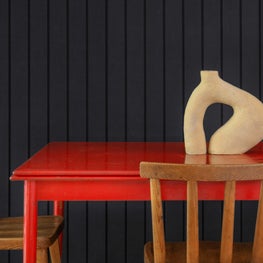 Dining area with sleek red table, black paneled walls, objet d'art centerpiece