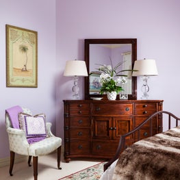  In this light lavender painted bedroom the antique walnut chest adds warmth.