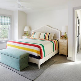 Lake Geneva Bedroom. Multi-colored camp blanket on ivory cane bed with green buffalo check shades & a sitting room.