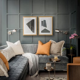 Family room with paneled wall and velvet sectional designed by Robin Gannon Interiors